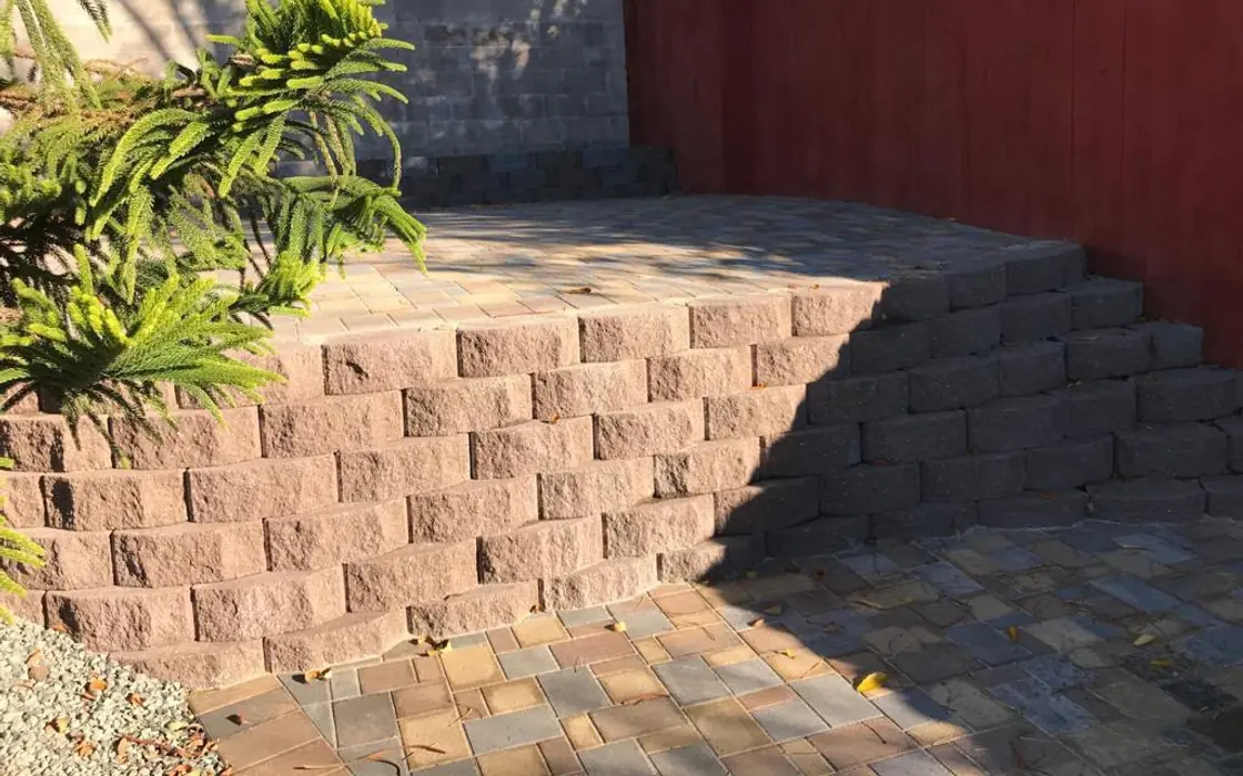 Finished paver patio with stacked-block retaining wall and red wood privacy fence. Fence & gate installation in Beaverton