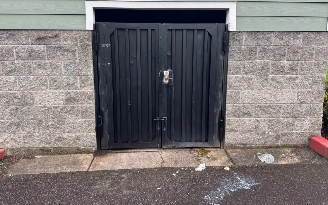 Black steel double swing gate with keypad in block wall opening, some wear. Fence & gate installation in Boring