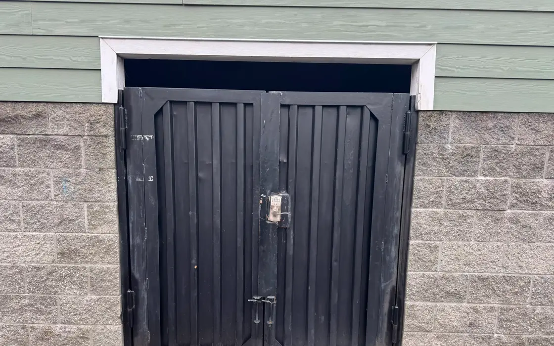 Weathered black steel double swing gate with keypad and cane bolts in block wall. Fence & gate installation in Estacada