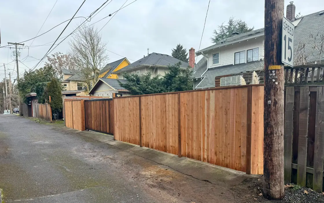 Long new cedar privacy fence with integrated slide gate along residential alley. Fence & gate installation in Gladstone