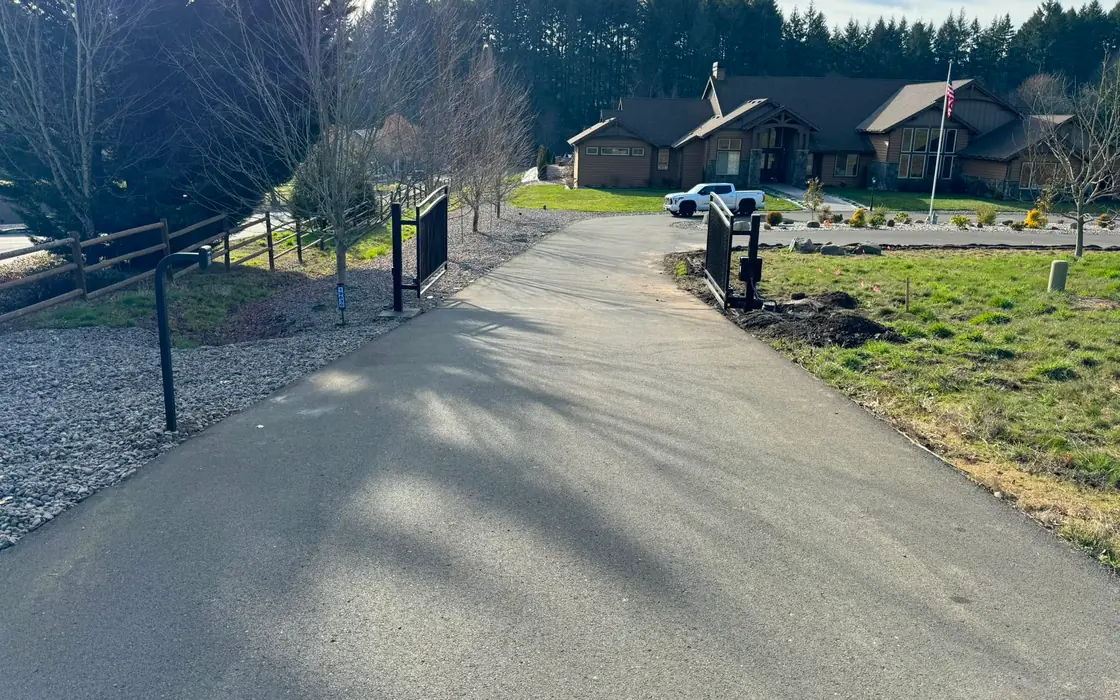 Open black metal dual-swing driveway gate with automation, craftsman home beyond. Fence & gate installation in Hillsboro