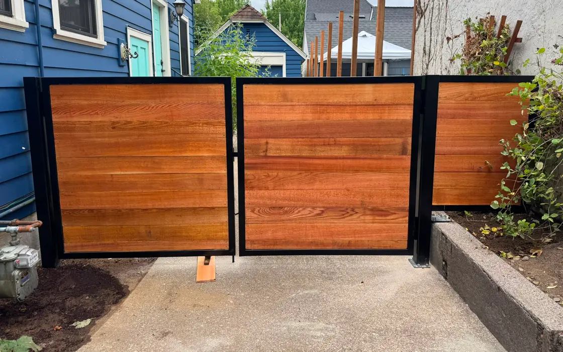 Horizontal cedar wood swing gates with black steel frames between houses. Fence & gate installation in Portland
