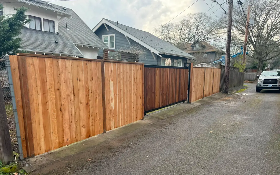 Long cedar privacy fence with slide gate along alley, work truck parked nearby. Fence & gate installation in Sherwood