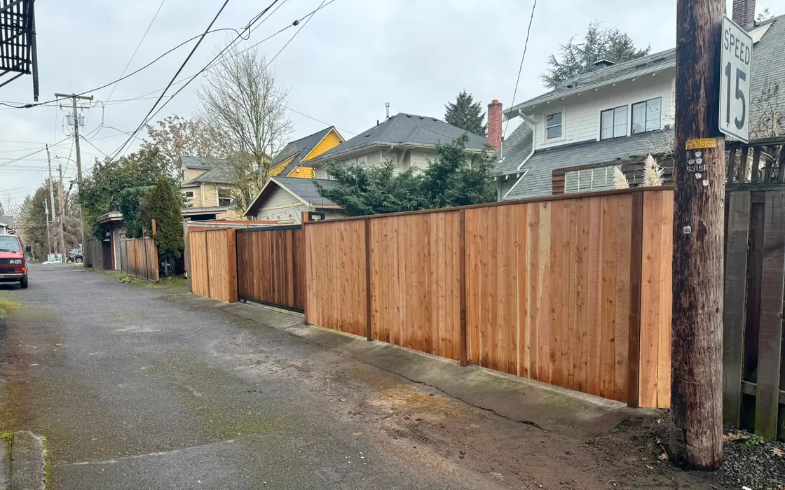 New cedar privacy fence with slide gate running along alley near speed 15 sign. Fence & gate installation in Wilsonville
