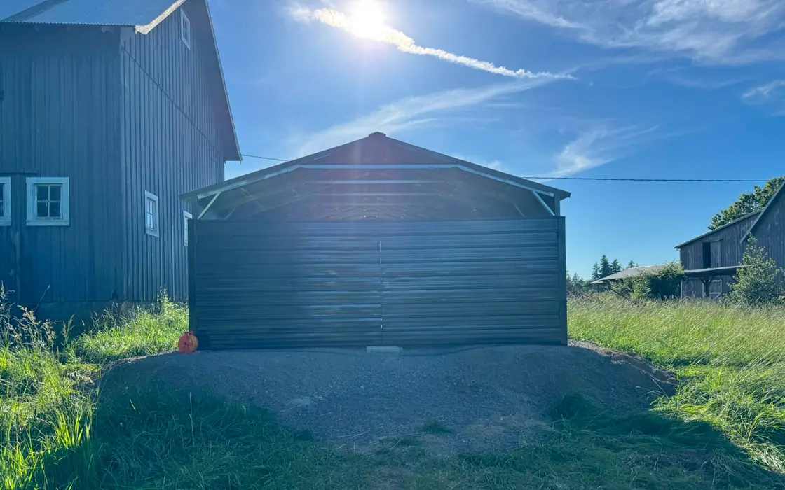 Dark metal double swing gate on steel carport in tall grass field. Fence & gate installation in Yacolt