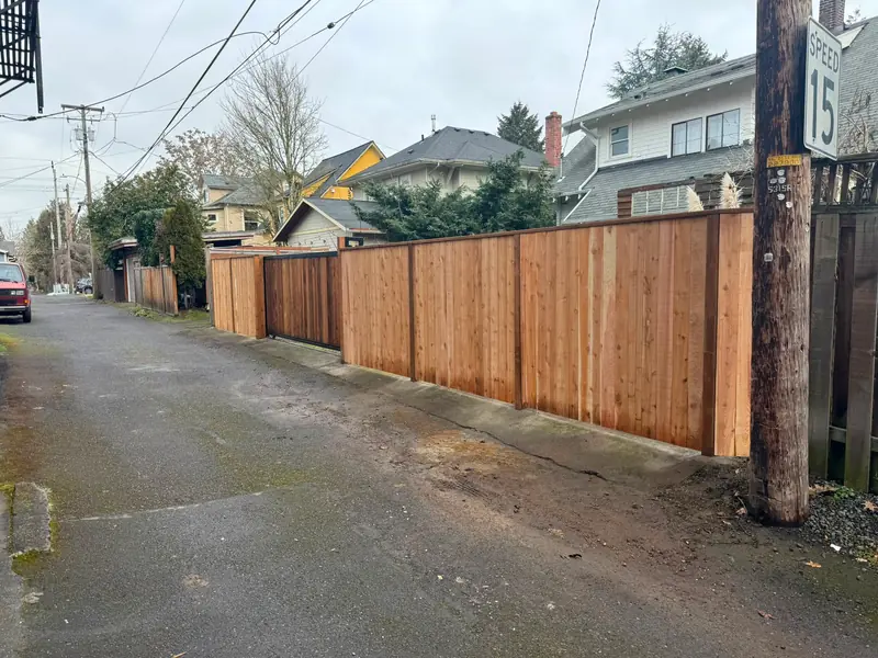 Board-on-board cedar fence. New cedar privacy fence with slide gate running along alley near speed 15 sign