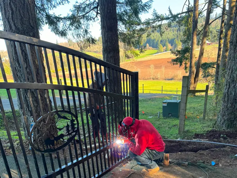 Custom-fabricated gate. Welder fabricating black driveway gate with elk emblem, Titanium welder onsite