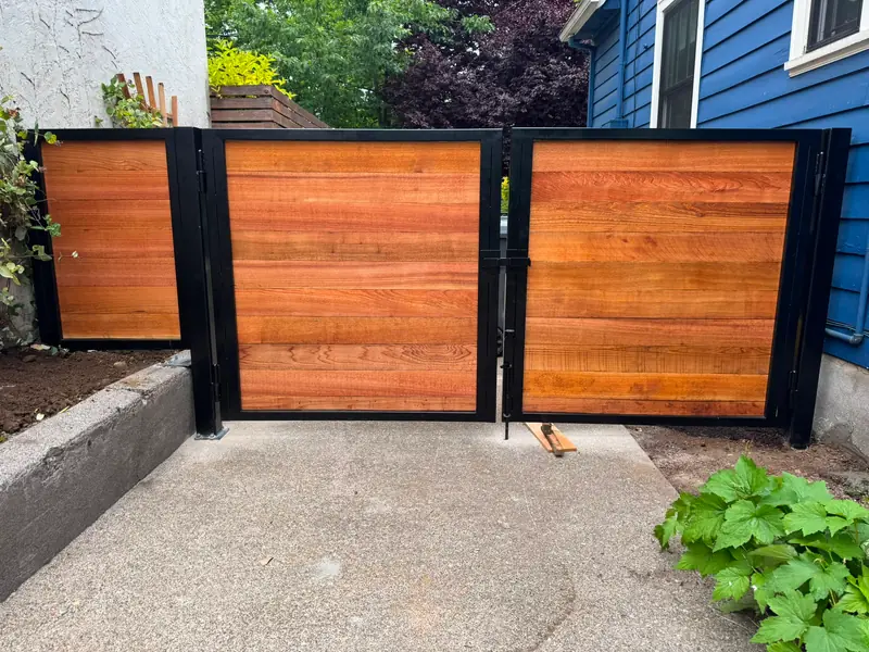 Ornamental entry gate. Horizontal cedar swing gates with black steel frames in narrow side yard