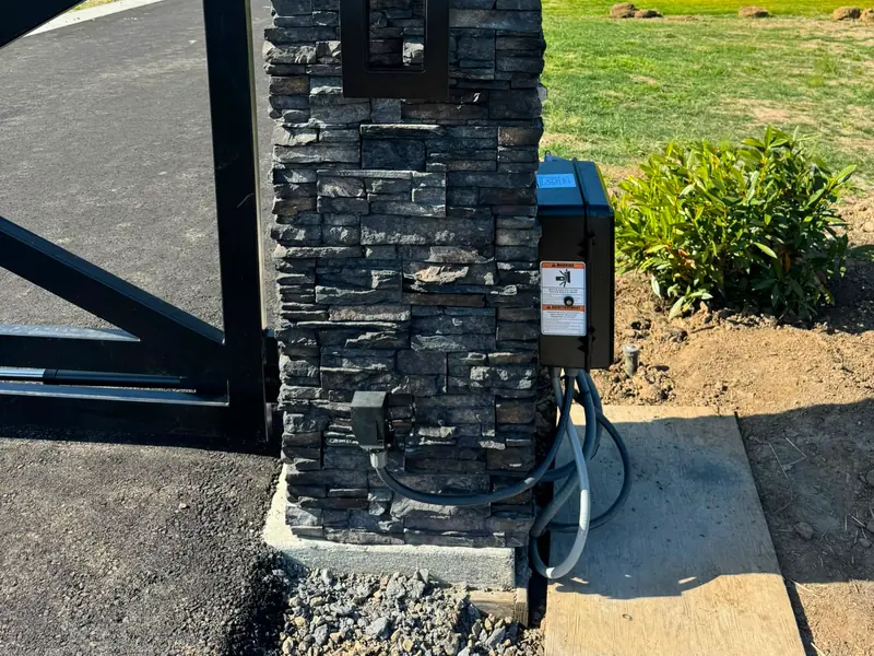 Gate opener install. Stacked-stone gate column with keypad, intercom and gate operator control box