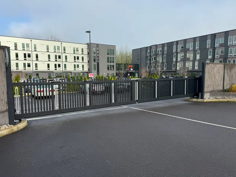 Black metal cantilever slide gate securing apartment parking lot at Casey building. Chain Link Fencing in Portland