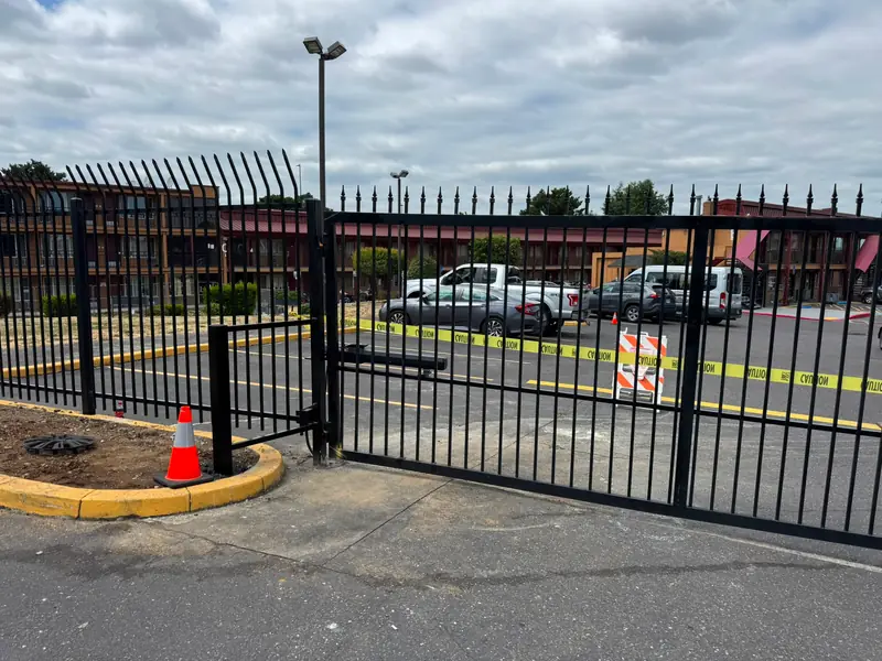 Black security iron slide gate and fence with operator at motel lot. Commercial Fencing in Portland