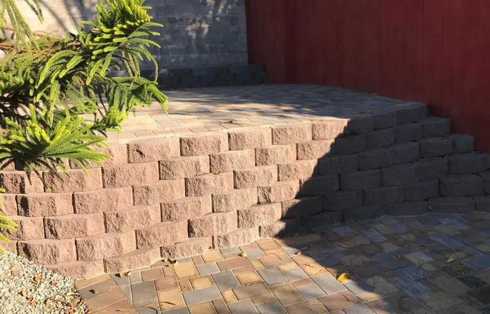 Finished paver patio with stacked-block retaining wall and red wood privacy fence. Fencing in Alberta Arts District