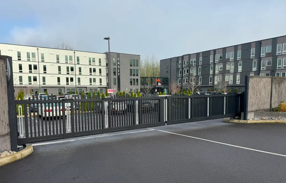 Black metal cantilever slide gate securing apartment parking lot at Casey building. Fencing in Bull Mountain