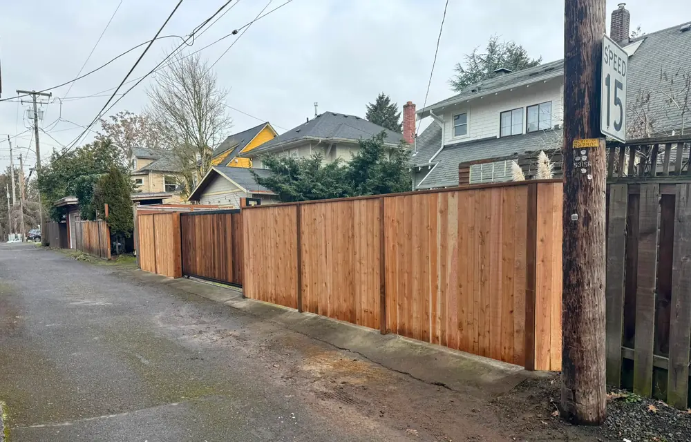 Long new cedar privacy fence with integrated slide gate along residential alley. Fencing in First Addition