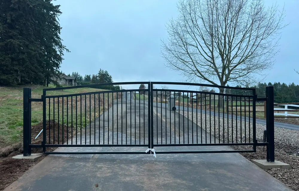 Finished black metal arched double swing driveway gate closed, wide frontal view. Fencing in Murrayhill