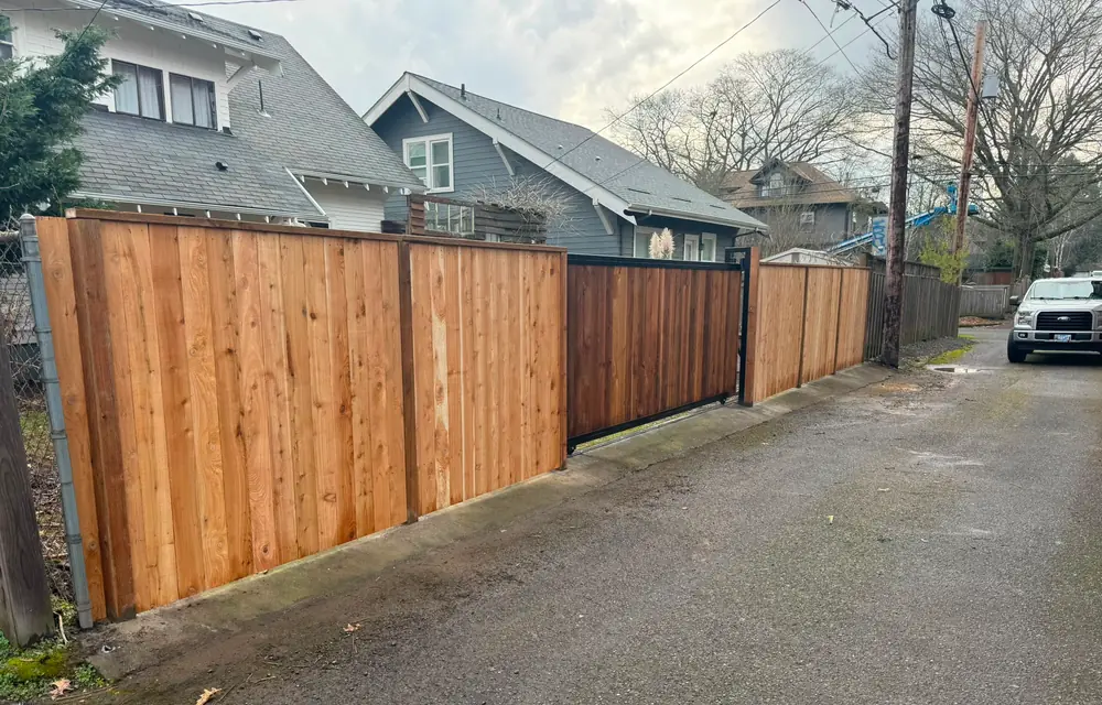 Long cedar privacy fence with slide gate along alley, work truck parked nearby. Fencing in St. Johns