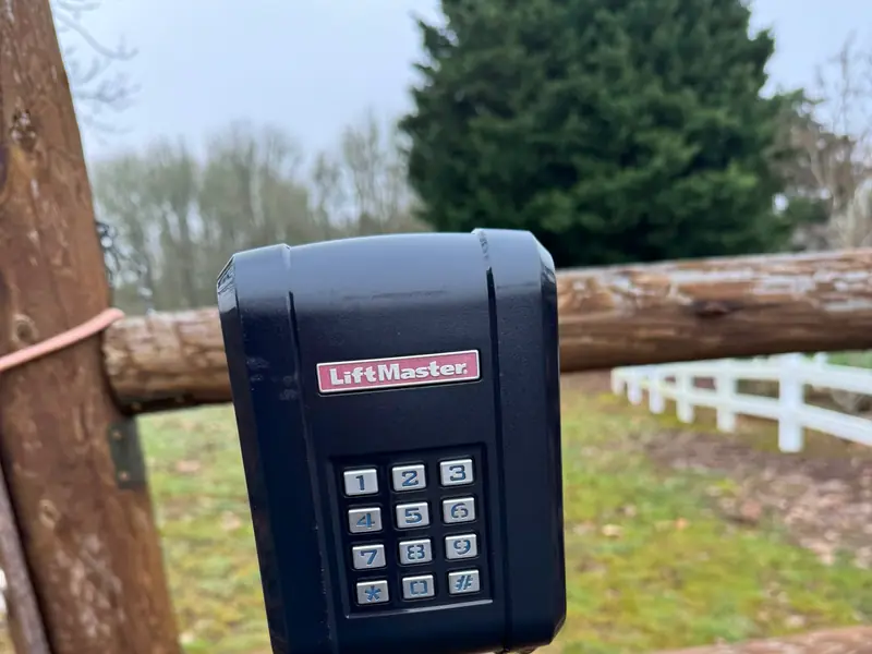 LiftMaster keypad closeup on post at rural property with white fence behind